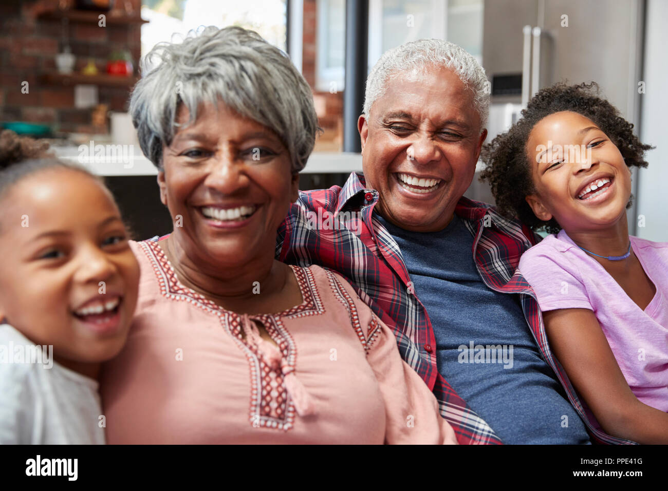 Ritratto di nonni seduti sul divano di casa con nipoti Foto Stock