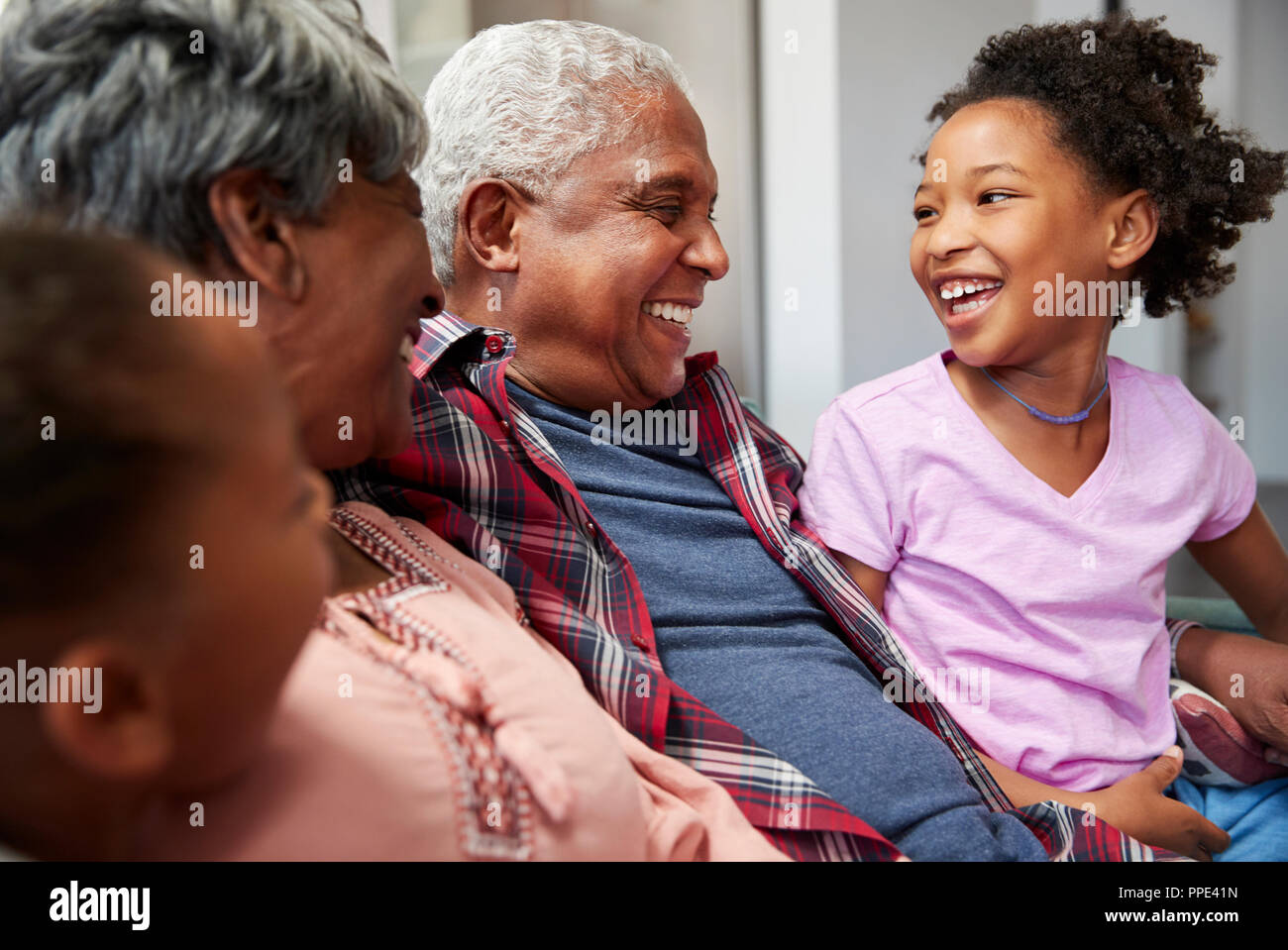 Nonni rilassante sul divano in casa con i nipoti Foto Stock