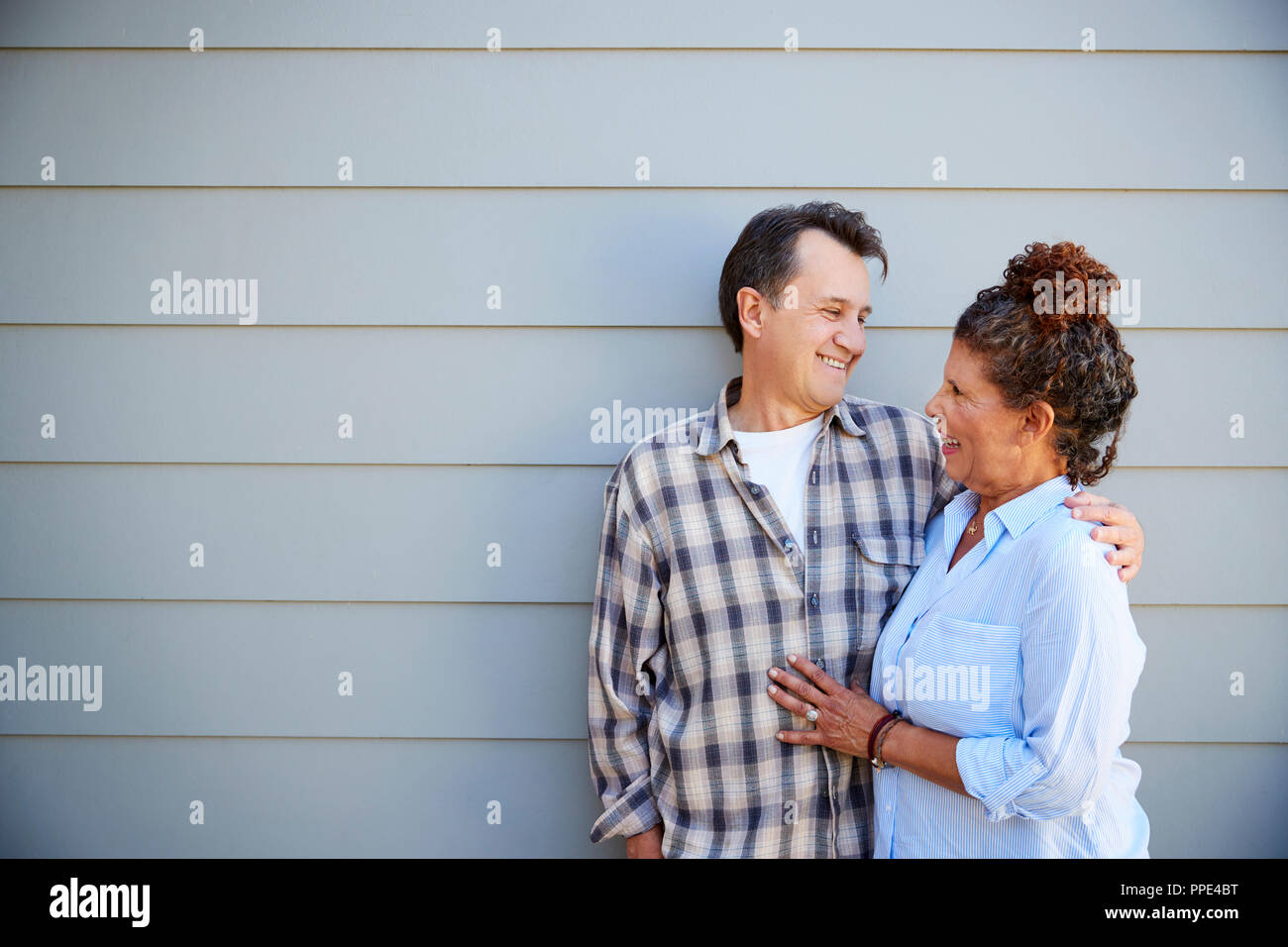 Coppia senior in piedi fuori clapboard grigie House Foto Stock