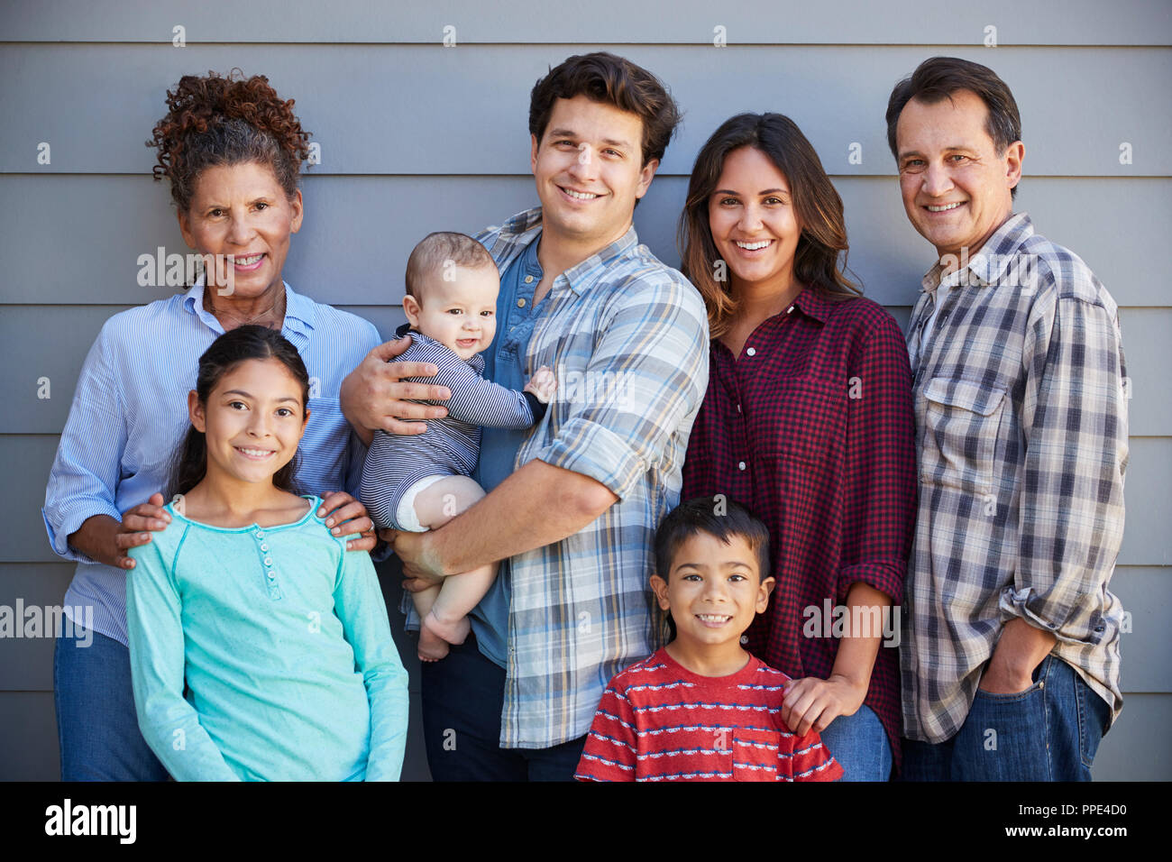 Ritratto di Multi generazione famiglia con bambino in piedi fuori clapboard grigie House Foto Stock