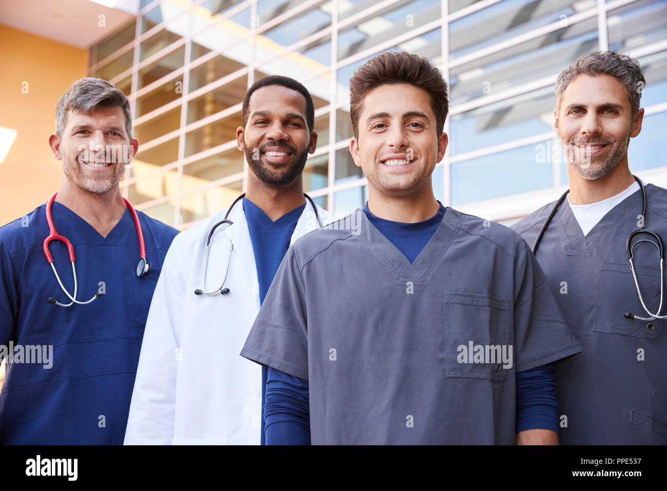 Quattro maschi healthcare colleghi in piedi all'aperto, ritratto Foto Stock