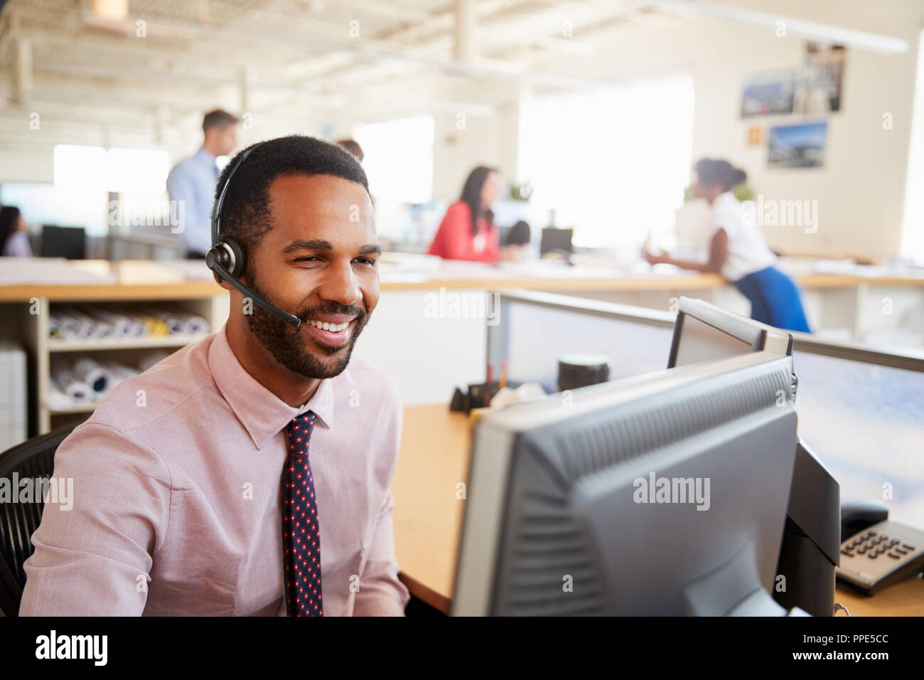 Maschio sorridente call center lavoratore guardando lo schermo, close-up Foto Stock