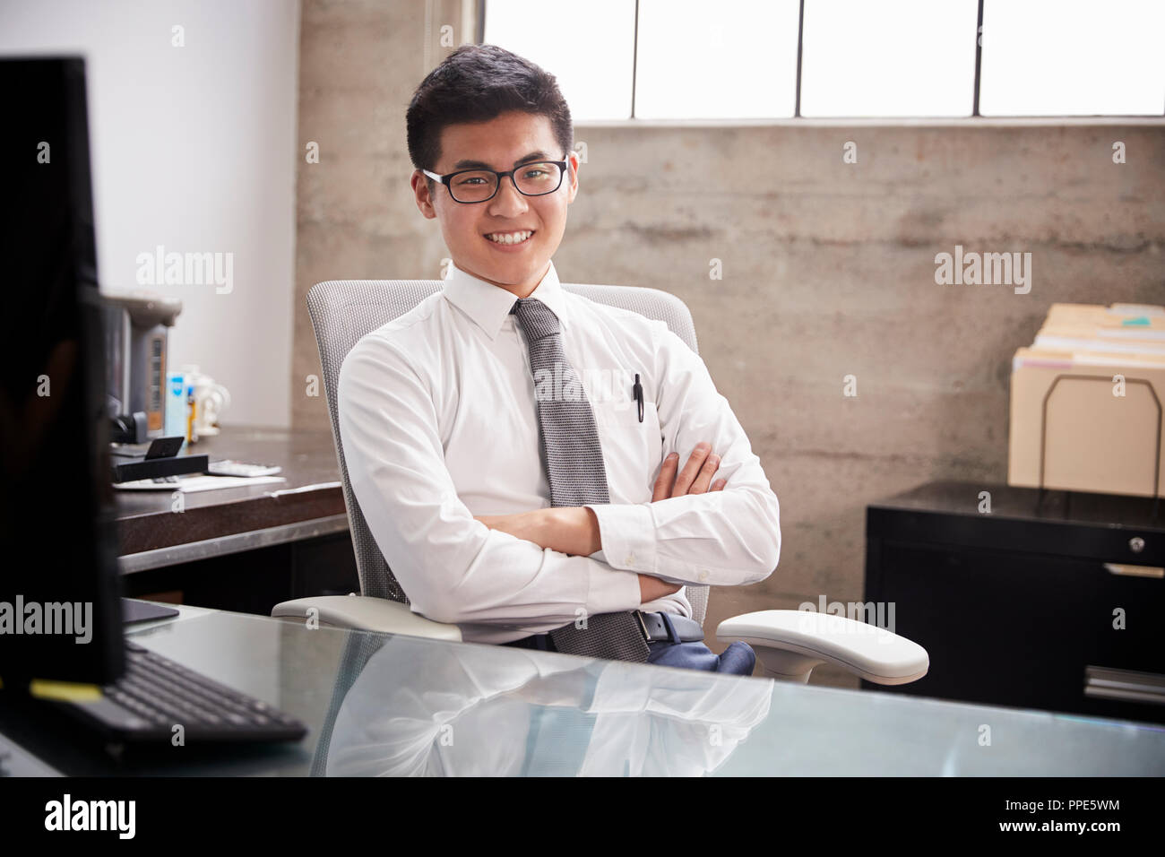 Giovane imprenditore asiatici presso un ufficio di accoglienza sorridente alla fotocamera Foto Stock