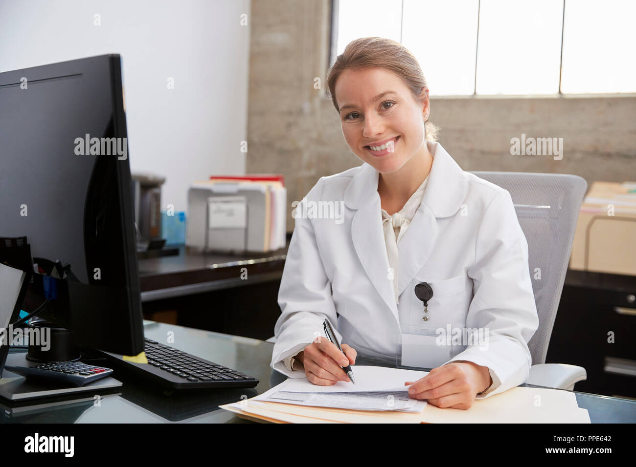 Bianco giovane medico donna alla scrivania in ufficio, ritratto Foto Stock