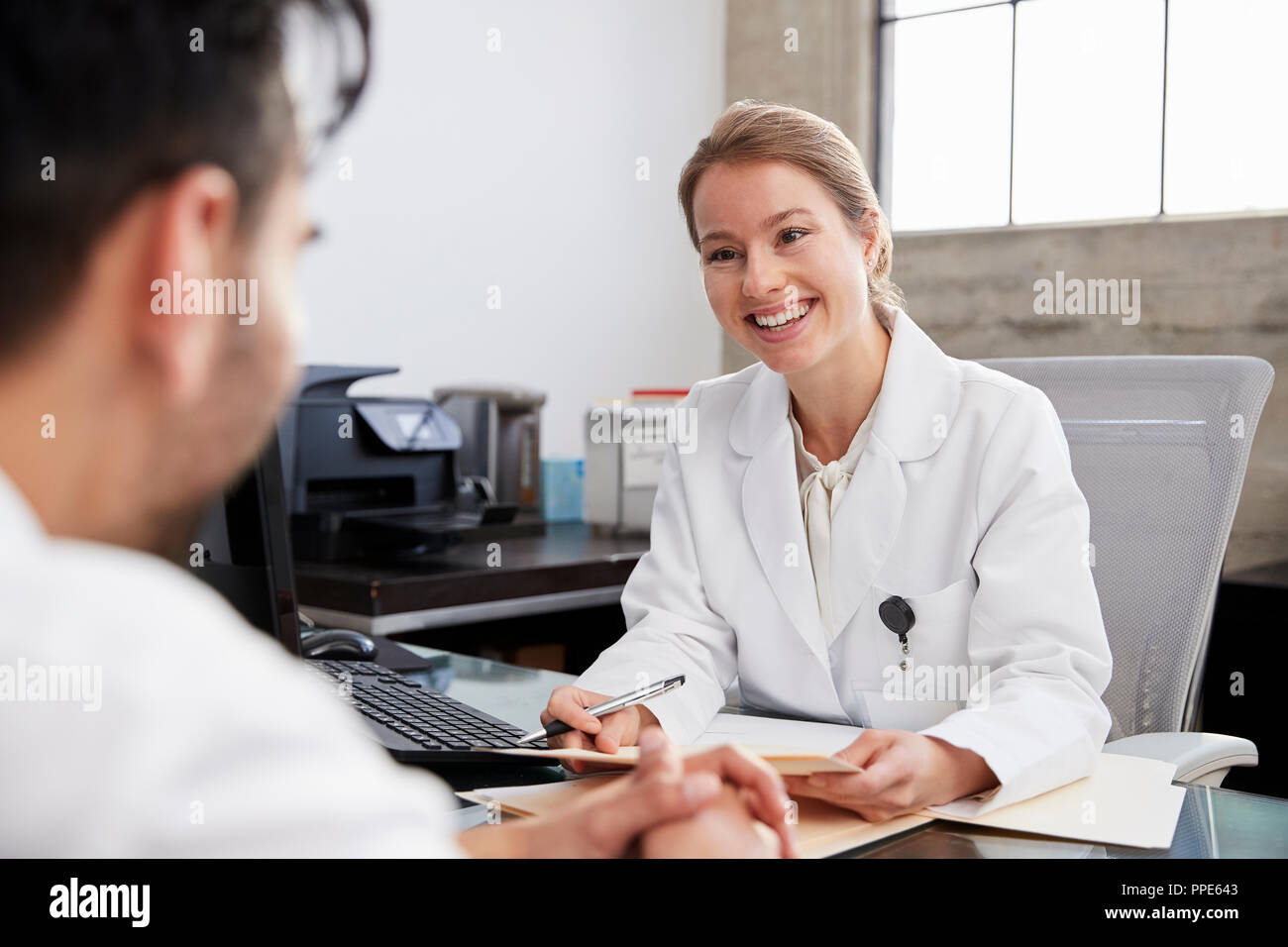 Donna sorridente medico in consultazione con il paziente di sesso maschile Foto Stock