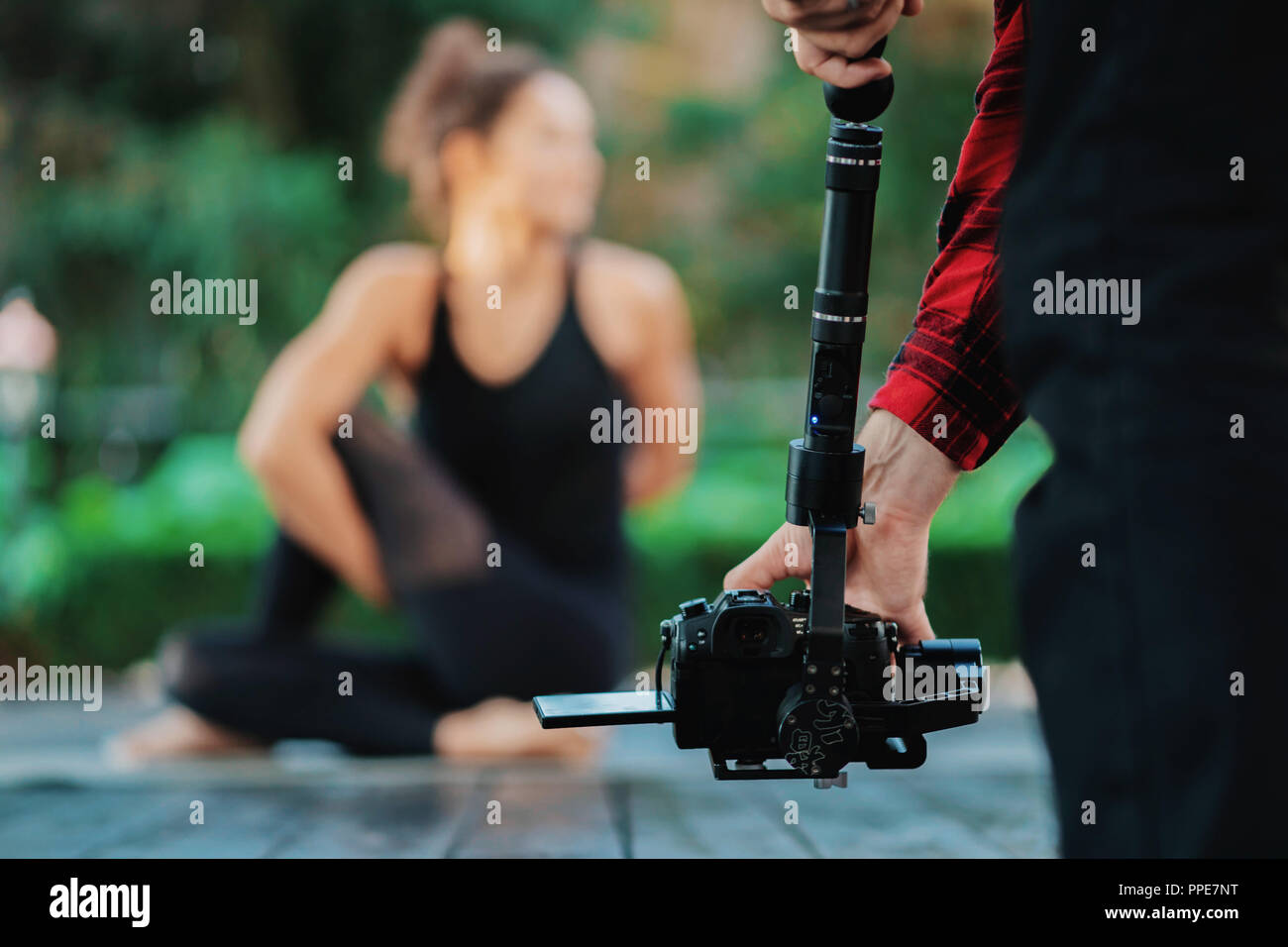 La telecamera video uomo operatore che lavora con attrezzature professionali,catturare la registrazione. Cameraman riprese video di yoga pratica azione Foto Stock