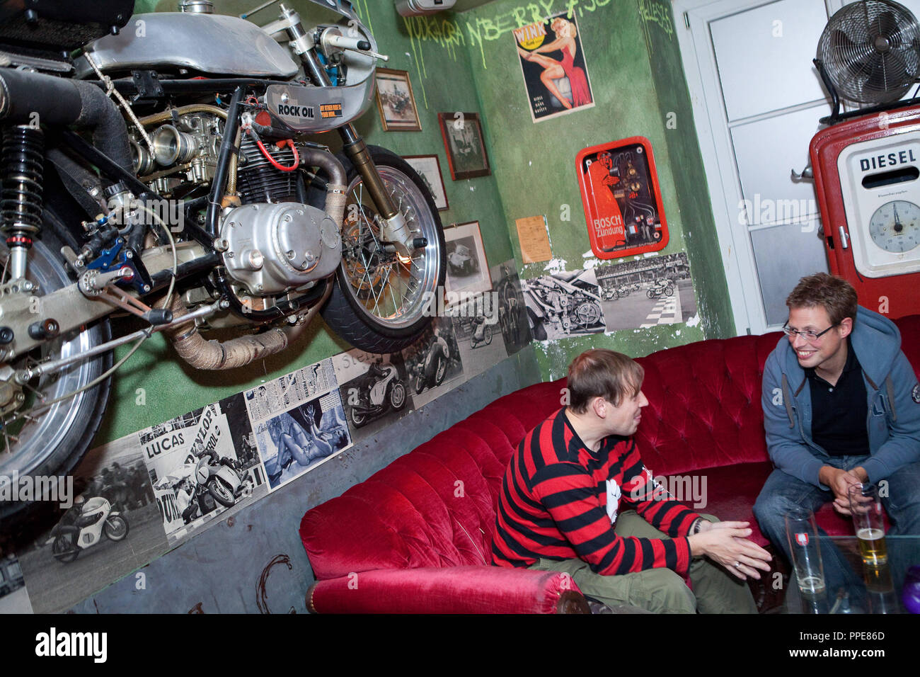 Gli ospiti presso lo studente bar 'Sehnsucht' in Amalienstraße, Maxvorstadt a Monaco di Baviera. Un motociclo è appeso alla parete Foto Stock