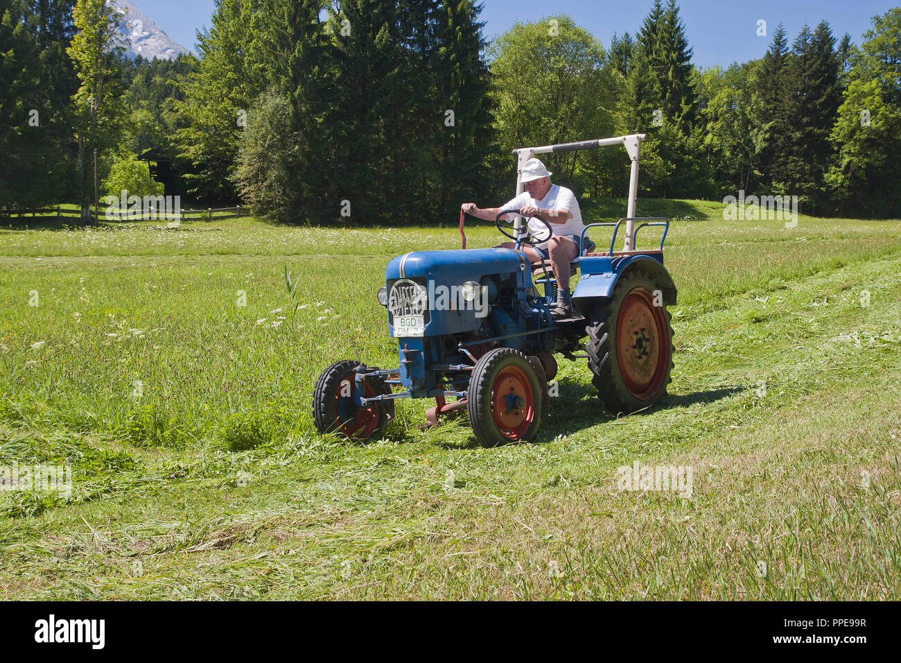 Un agricoltore mows il prato con trattore e barra falciante - un 'Oldtimer', Bavaria. Foto Stock