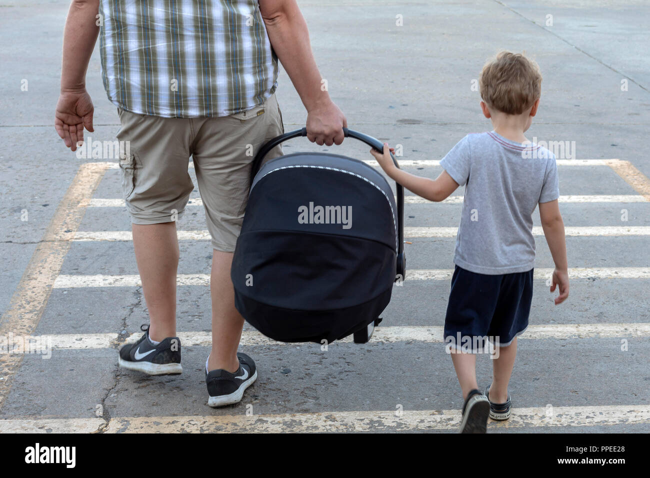 Wheat Ridge in Colorado - Adam Hjermstad Jr., 4, aiuta il suo papà portare un seggiolino per auto contenenti il suo fratellino. Foto Stock