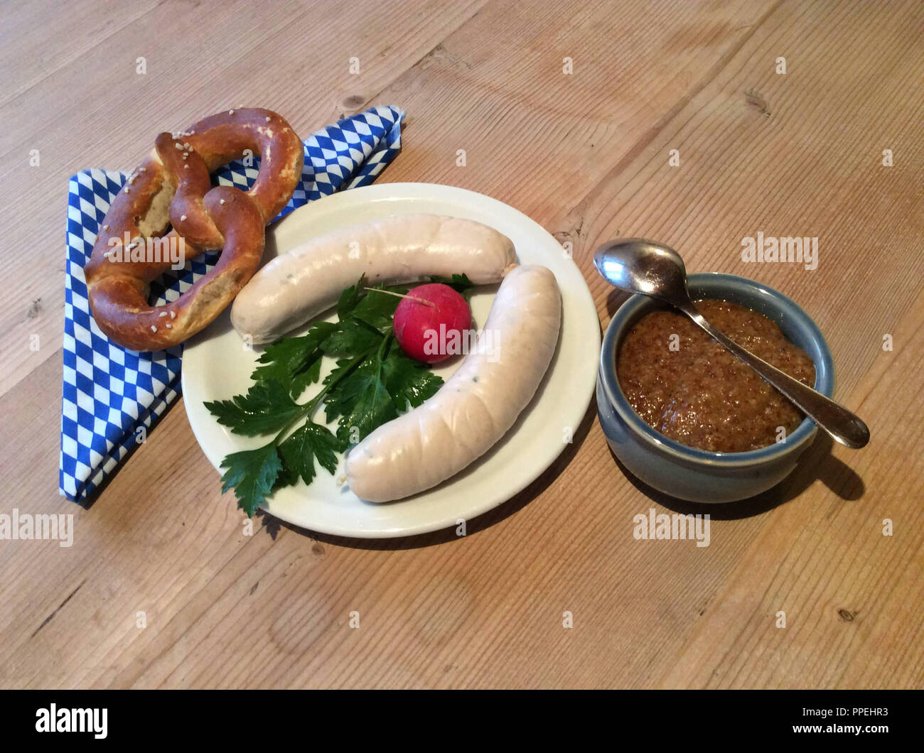 Weisswurst snack o colazione con pretzel, Rafano, prezzemolo e senape su una tavola in legno rustico. Foto Stock