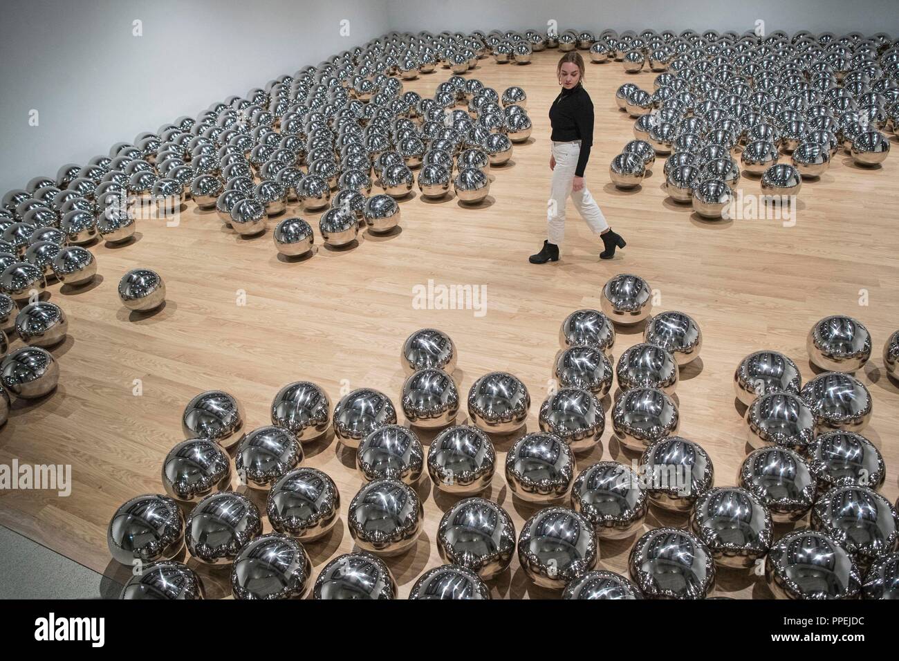 Una donna opinioni 'Giardino di Narciso 1966-' di Yayoi Kusama, realizzati in acciaio inossidabile sfere, durante una anteprima di stampa per la mostra: traslatori di spazio presso la Hayward Gallery, Southbank Centre di Londra. Foto Stock