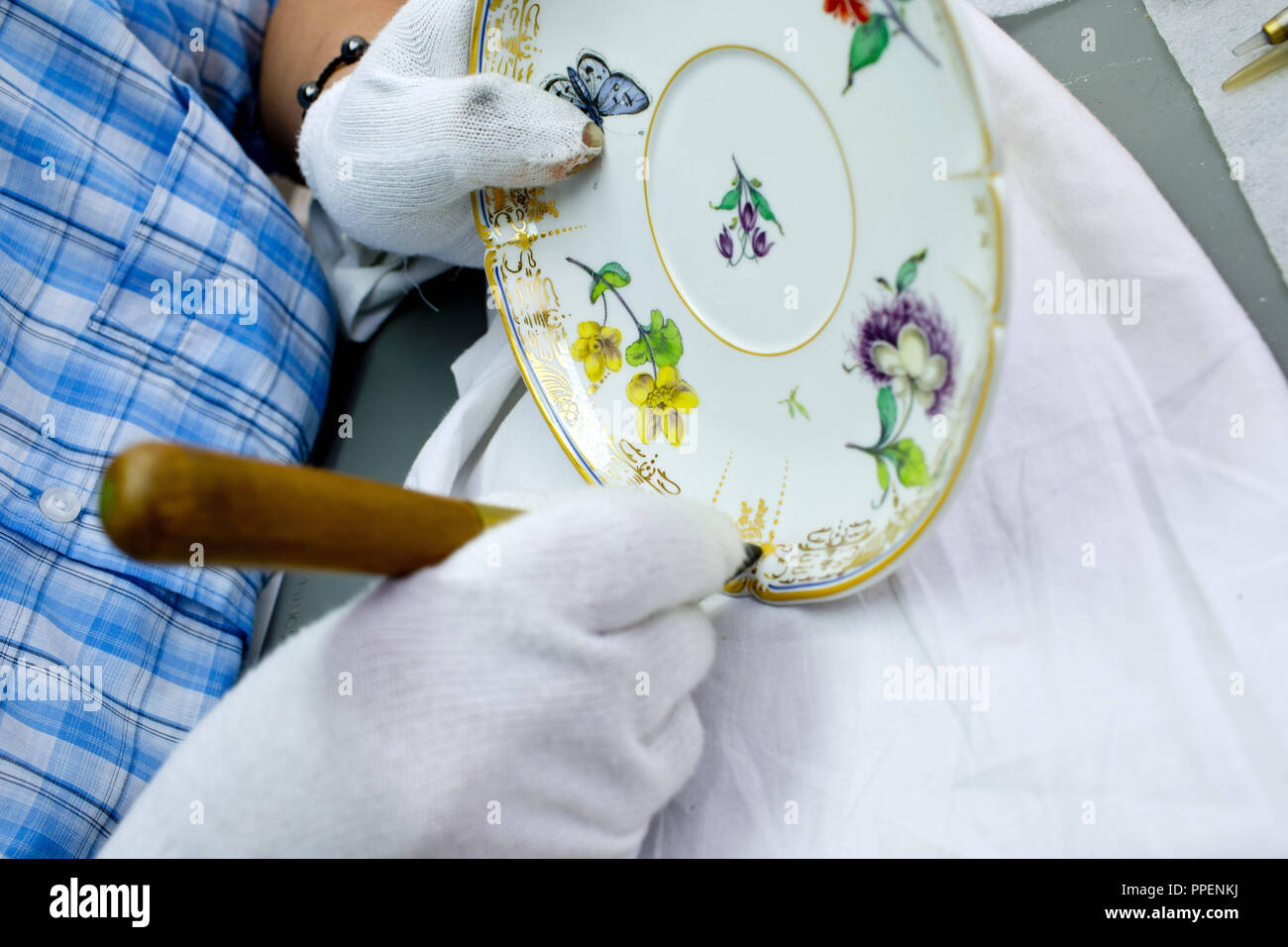Un oro polacco è applicata su una piastra nel castello di Nymphenburg manifattura di porcellana a Monaco di Baviera. Foto Stock