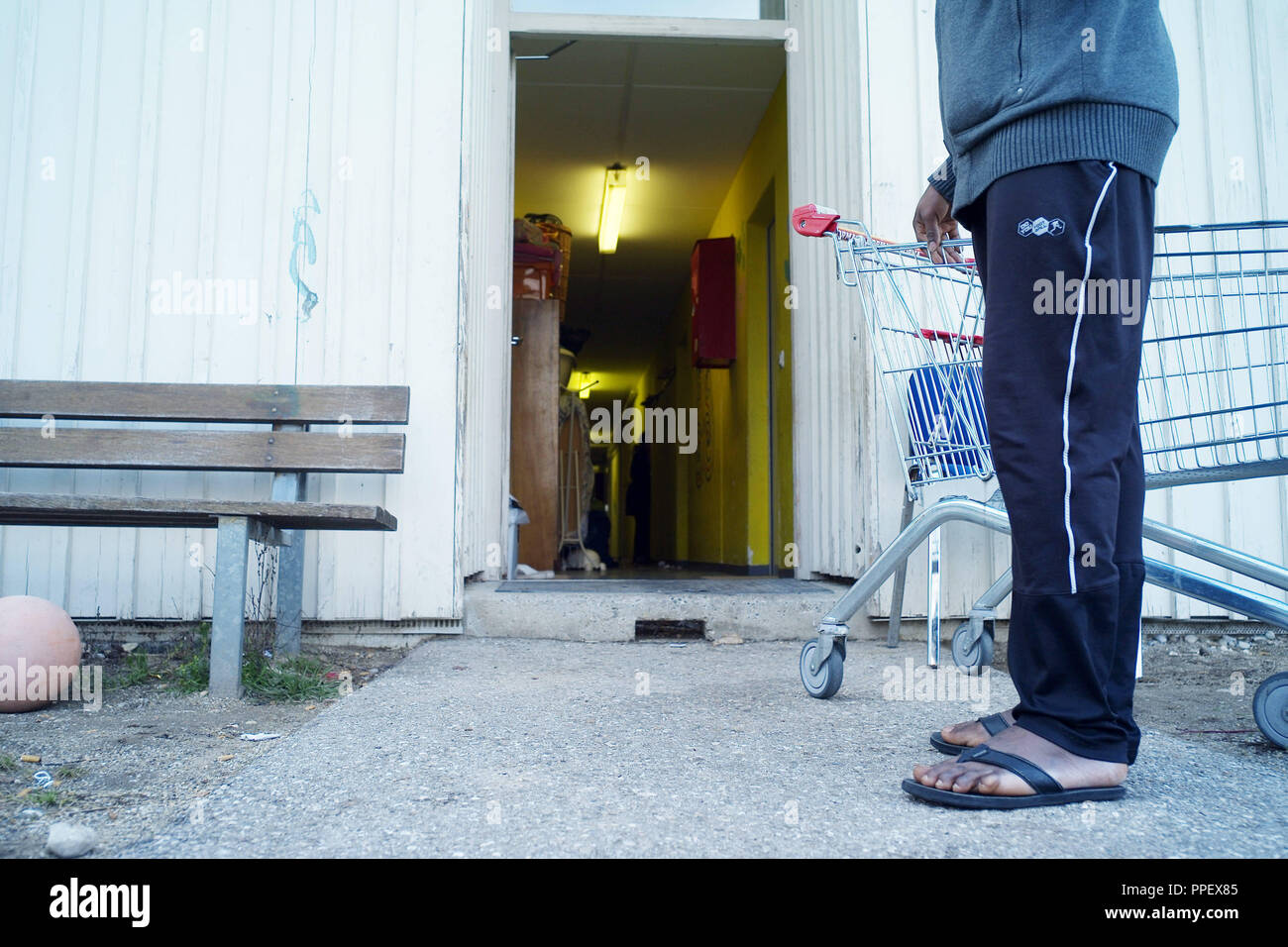 Richiedenti asilo in pantofole con un carrello all'ingresso della casa di accoglienza per i richiedenti asilo di Germering. Foto Stock