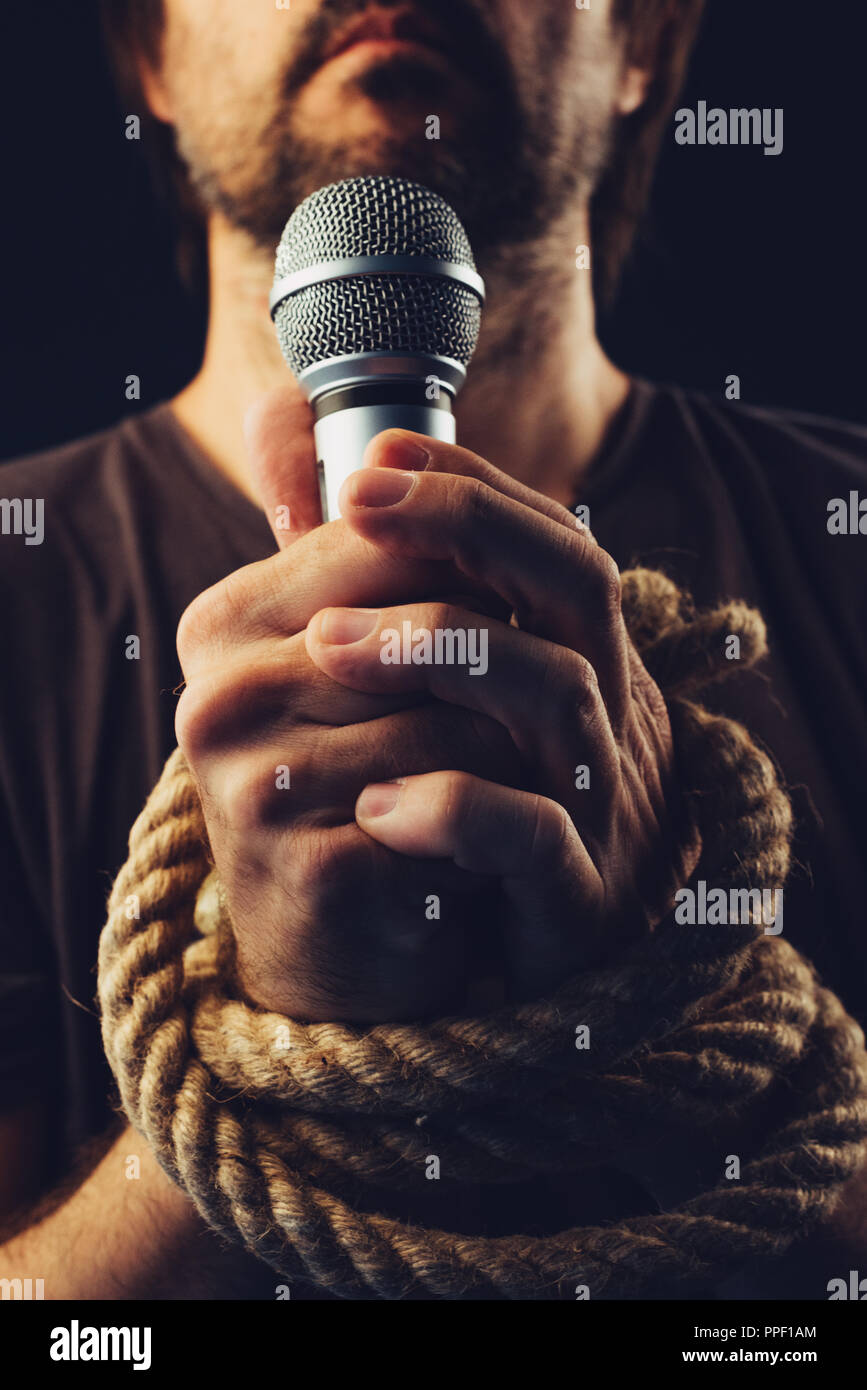 La libertà di parola, immagine concettuale con maschio persona in possesso di un microfono con le mani legate in corde, bassa immagine chiave Foto Stock
