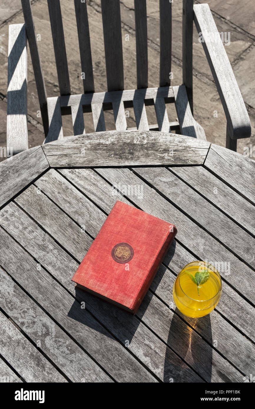 Un libro e un bicchiere di bevanda a base di frutta su un tavolo di legno. Foto Stock