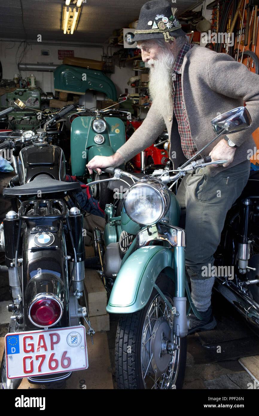 Guida Alpina e membro della band Garmisch-Partenkirchen originale, Sepp Inverno nel suo garage con la sua collezione di moto. Foto Stock