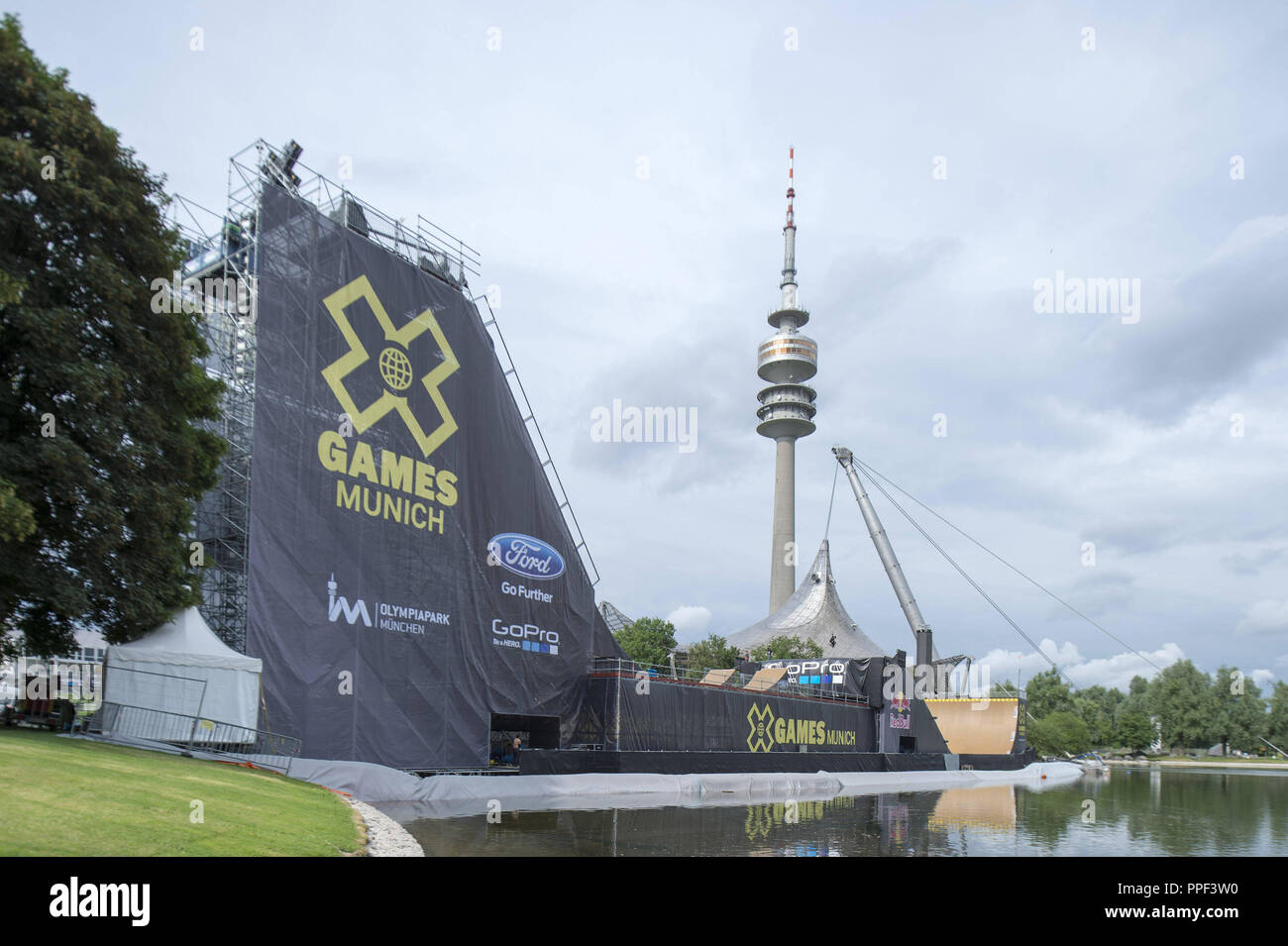 Un guidatore di skateboard treni sulla grande rampa sul lago olimpico per lo skateboard Big Air finale al X-Games Monaco di Baviera. Sullo sfondo la torre olimpica. Foto Stock