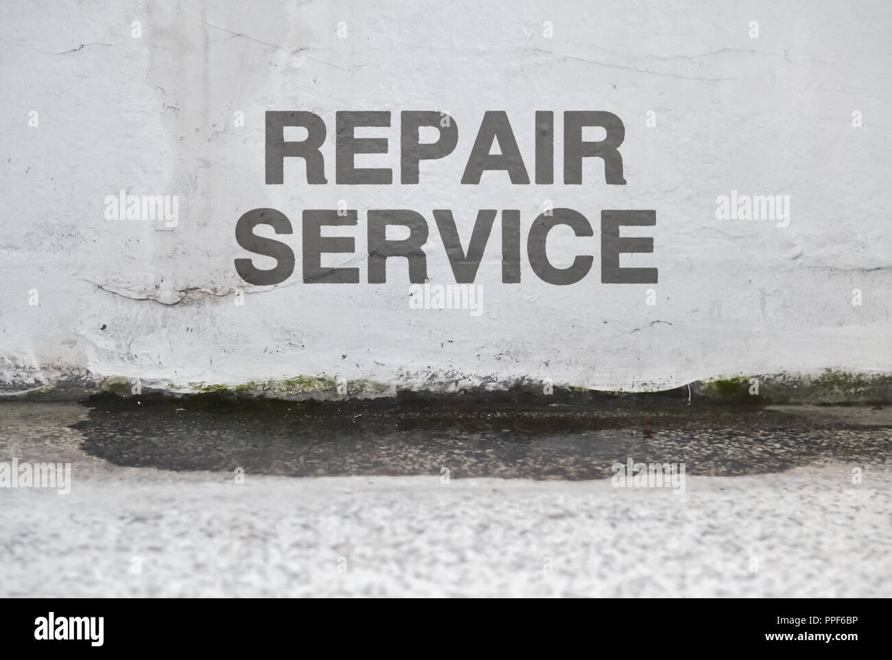 Testo di servizio di riparazione su un danneggiamento della parete umida che necessita di rinnovo Foto Stock