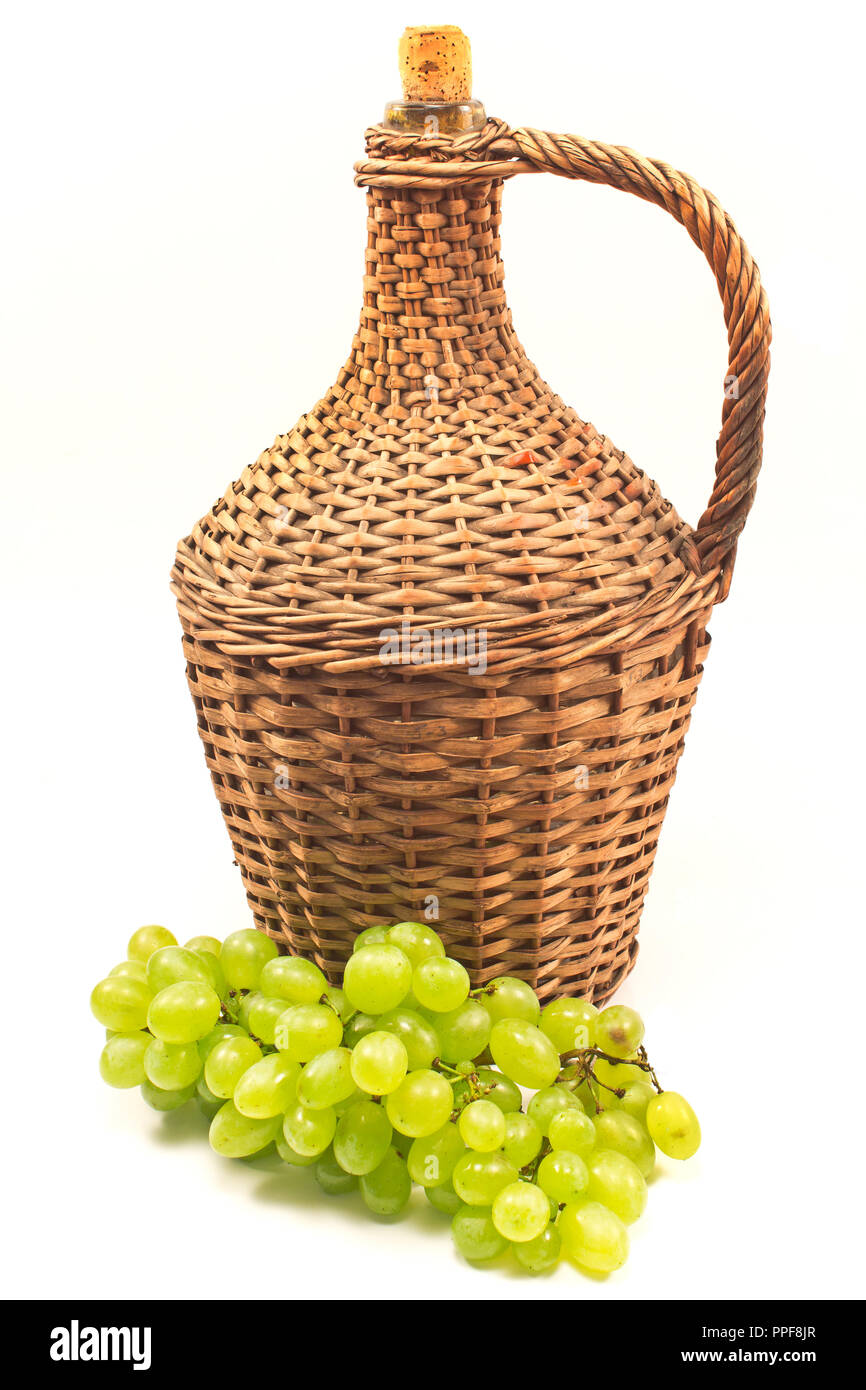 Uva bianca con il vecchio avvolto in vimini bottiglia di vetro isolato su bianco Foto Stock