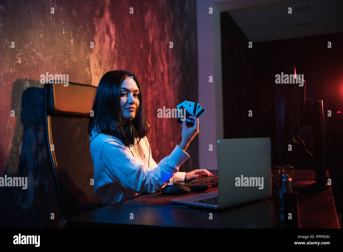 Primo piano della giovane femmina theift in felpa con cappuccio il trasferimento di denaro dalle bollette di furto di carte creding Foto Stock