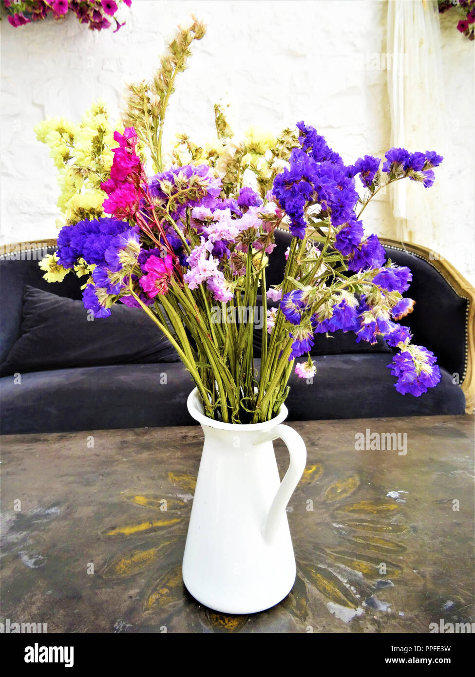 Composizione della bella essiccati fiori colorati in un vaso bianco su un vecchio tavolo Foto Stock