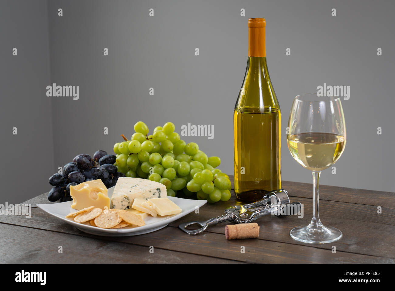 Bicchiere di vino bianco con bottiglia di vino, formaggio e uva Foto Stock