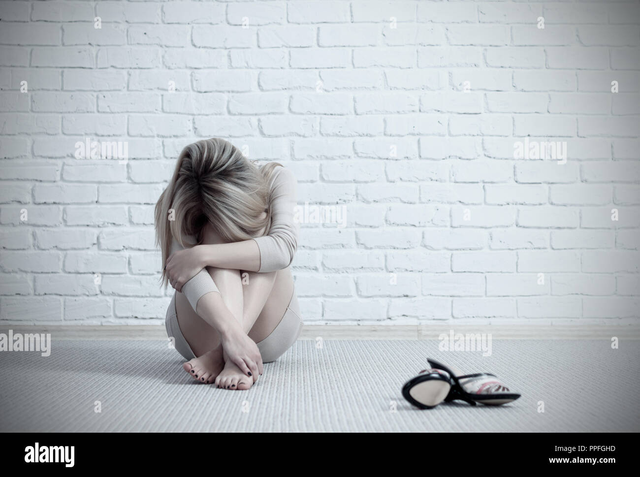 Triste giovane donna seduta sul pavimento e pianto Foto Stock