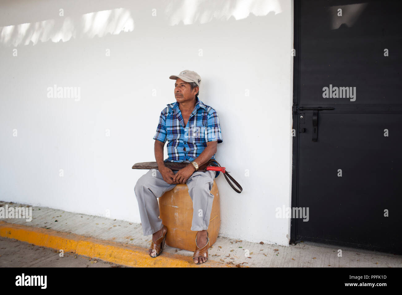 Un vigilante a stati di UPOEG (popoli' europea e delle organizzazioni da parte dello Stato di Guerrero), stand nelle ombre mentre il suo gruppo raccoglie donazioni, il 17 novembre 2014, in Iguala, Messico. Il gruppo, che trasporta soltanto machete quando sono in viaggio al di fuori delle loro comuni locali, è stato in Iguala per quasi un mese aiutando con sforzi di ricerca di 43 studenti mancanti. Foto Stock