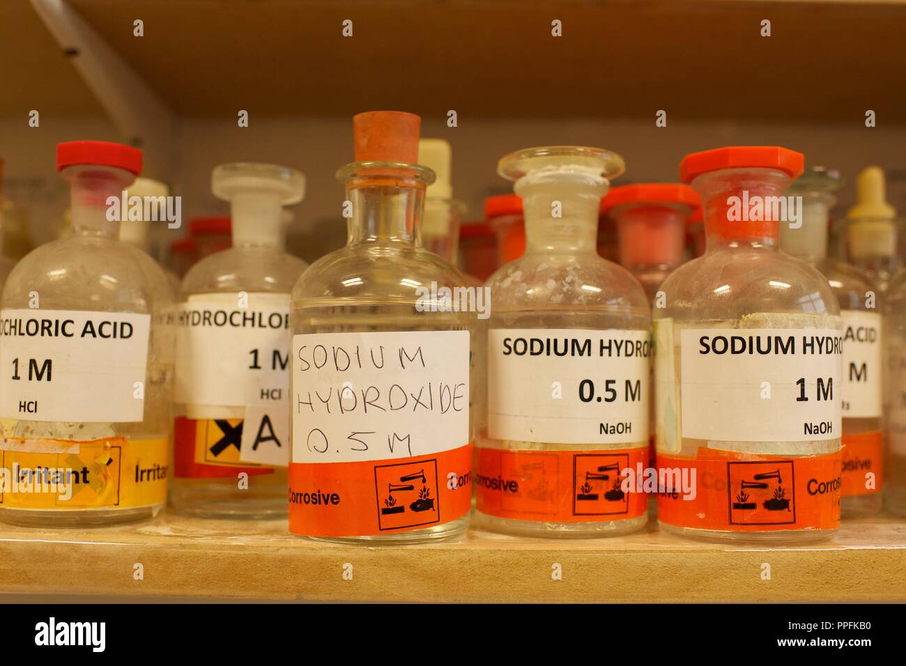 Varie bottiglie di sostanze chimiche inclusi idrossido di sodio in una scuola laboratorio di chimica Foto Stock