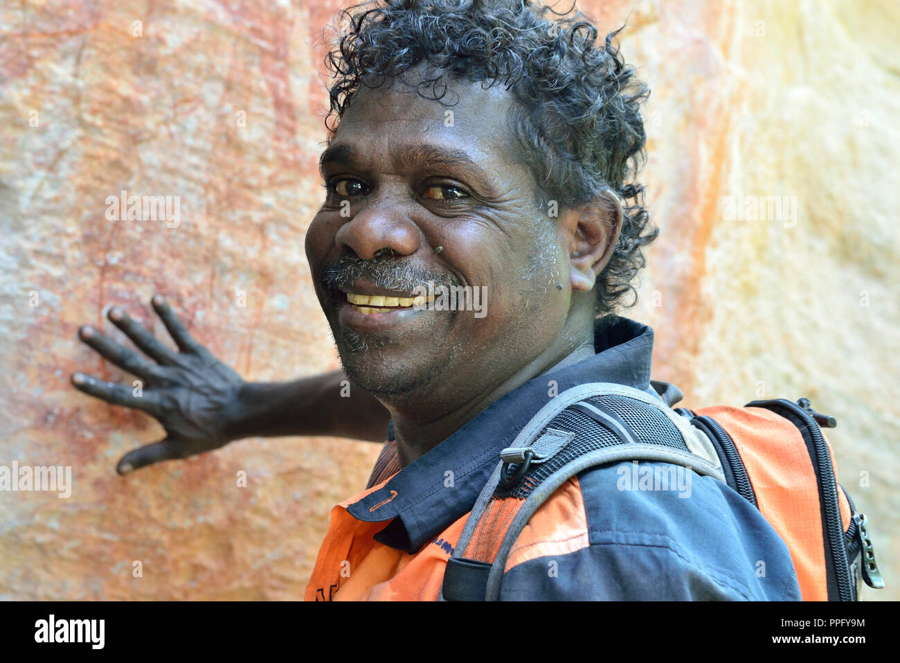 Guida aborigena sottolineando le opere in una roccia galleria d'arte sul colle Injalak di Arnhem Land, Territorio del Nord, l'Australia Foto Stock