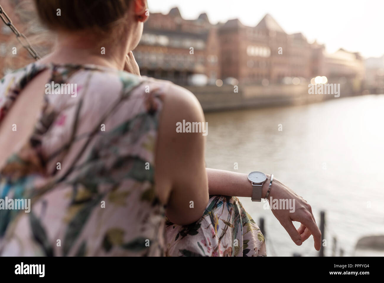 Vista posteriore della donna seduta oltre il fiume in città Foto Stock