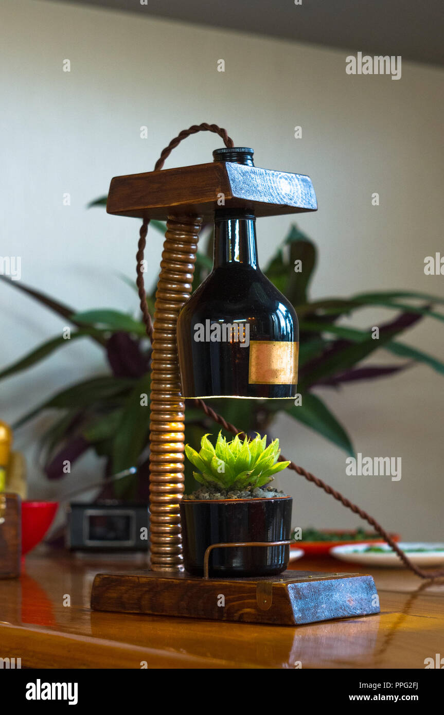 Apparecchio di illuminazione a mano - stand per i fiori in vaso in stile vintage, case in legno, raccordi in rame, Lampada led su uno sfondo nero. Foto Stock