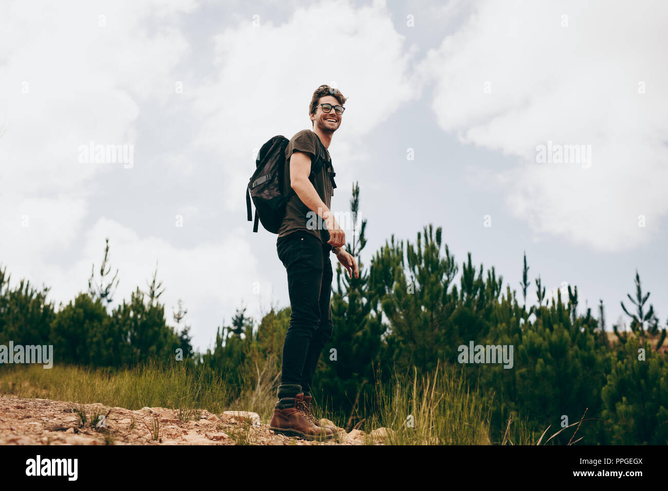 Uomo felice su una vacanza escursioni in una località di campagna. L'uomo trekking attraverso una foresta di indossare uno zaino. Foto Stock
