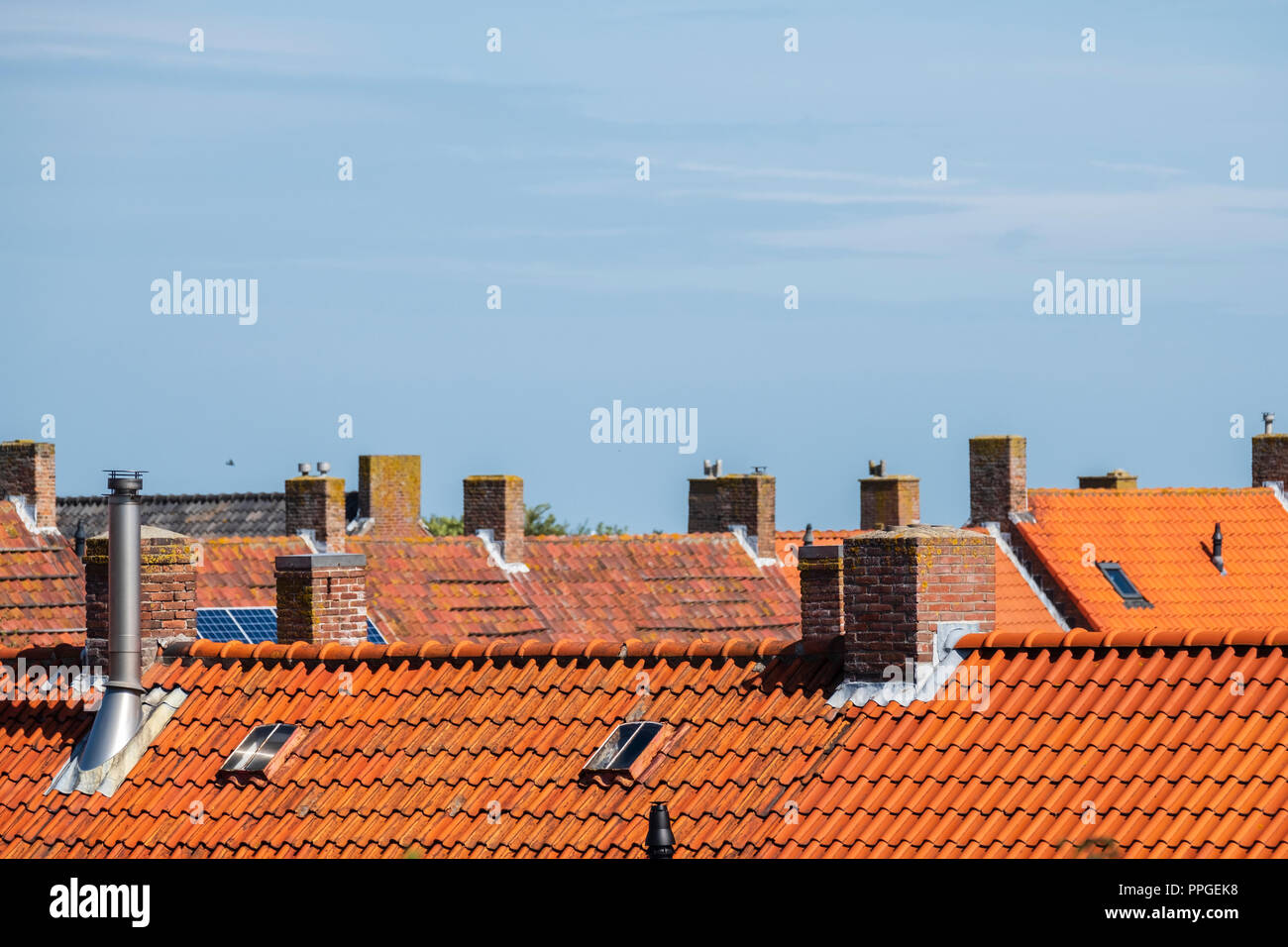 Camini in Pietra sui tetti con arancia tegole del tetto contro un cielo blu in un vecchio quartiere Foto Stock
