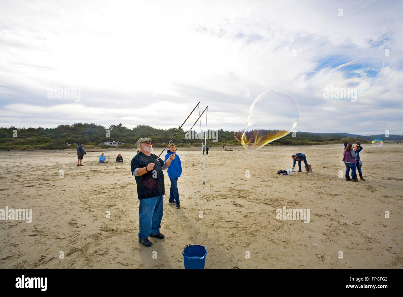 Un uomo con una bacchetta di bolla per creare enormi bolle di sapone in una bolla festival di soffiaggio vicino yachats, Oregon Foto Stock