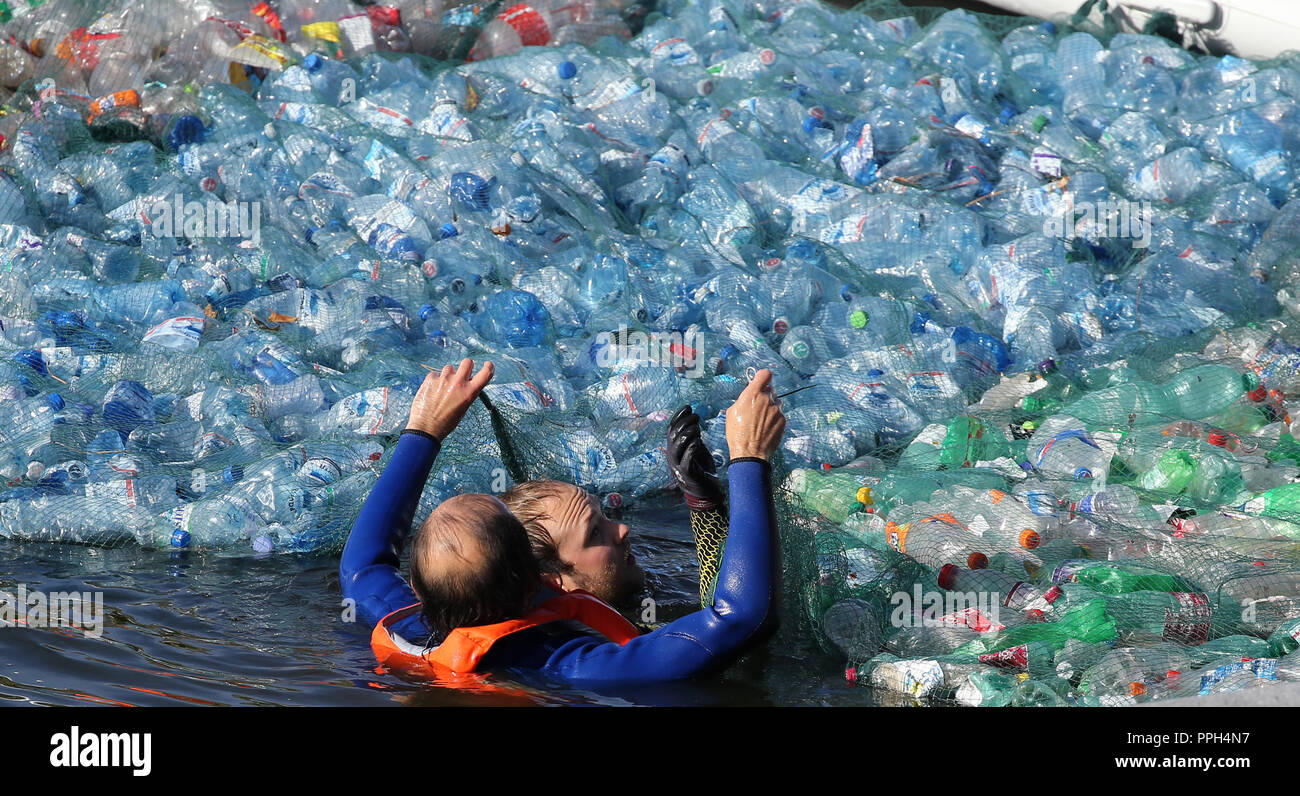 26 settembre 2018, Berlin: due uomini stanno preparando un 300 metri quadrati tappetino in plastica sulla Sprea di fronte al Reichstag, che è parte della manifestazione '#GoodbyePlasticBottles' contro l'aumento dei rifiuti di plastica. Foto: Wolfgang Kumm/dpa Foto Stock