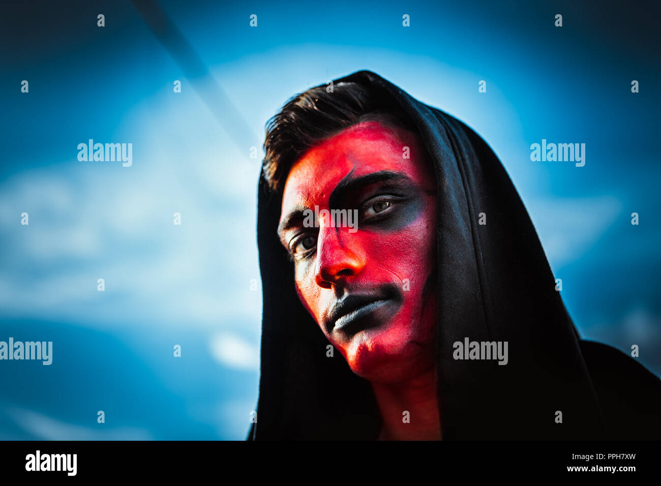 Rosso faccia demoniaca di un uomo contro il cielo. Foto Stock