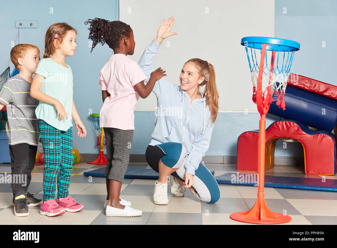 I bambini e il maestro dare un alto cinque al bambini ginnastica in sports hall della scuola Foto Stock