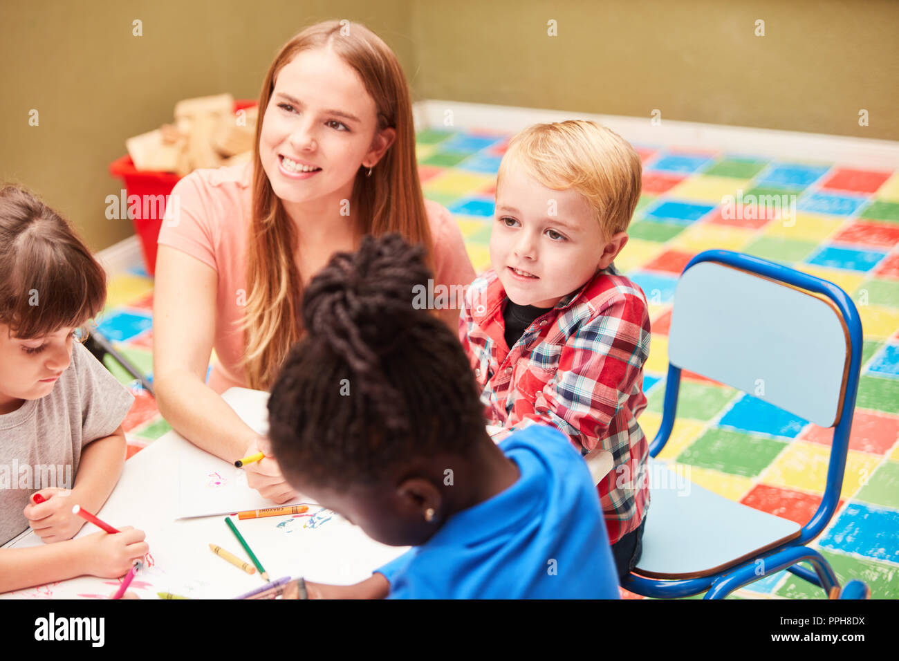 Insegnante di scuola materna o vernici insegnante insieme con i bambini nel corso di disegno del giorno-centro di cura Foto Stock