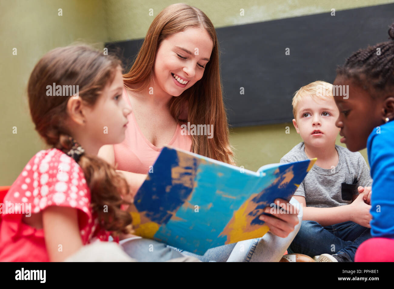 Gruppo di bambini e gli educatori di lettura da un libro per bambini o storybook Foto Stock