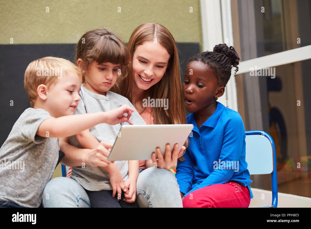 Insegnanti e bambini divertirsi imparando con un computer tablet nel centro diurno Foto Stock