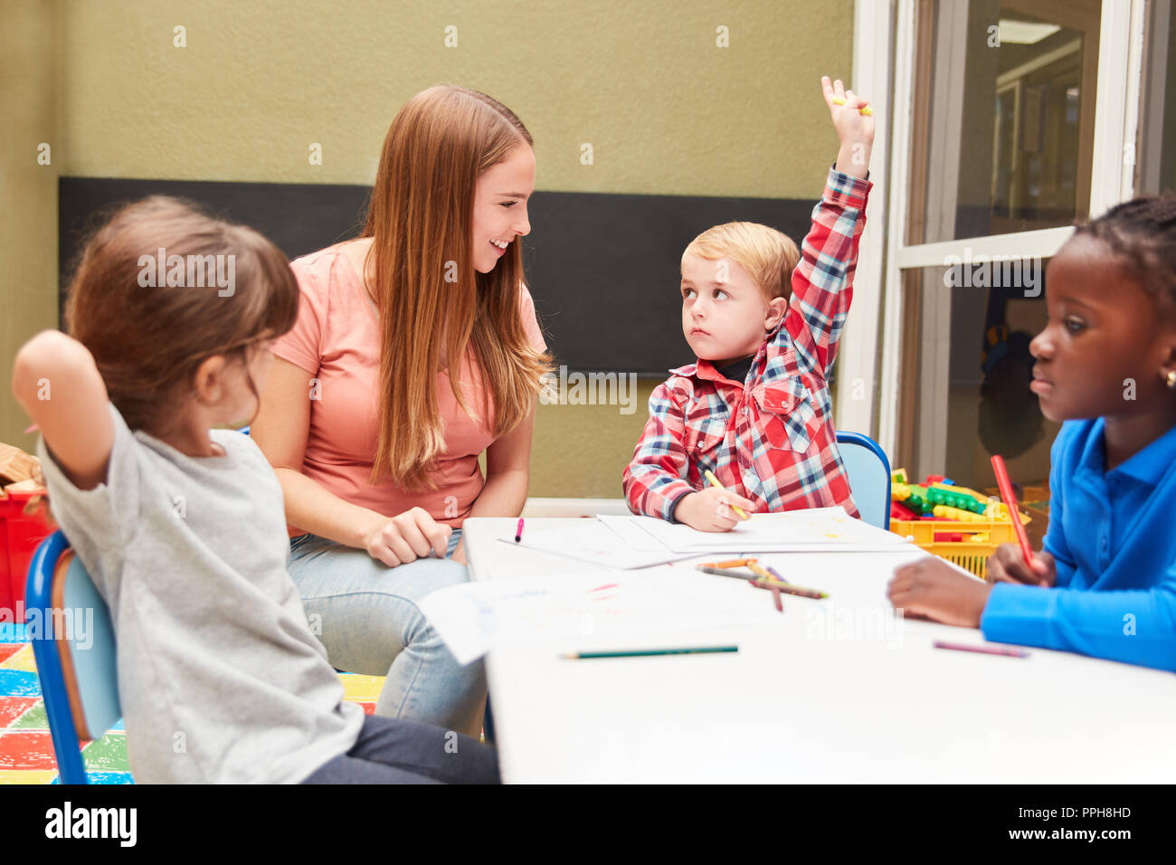 Ragazzo risponde a una domanda da parte dell'insegnante di arte classe in età prescolare Foto Stock