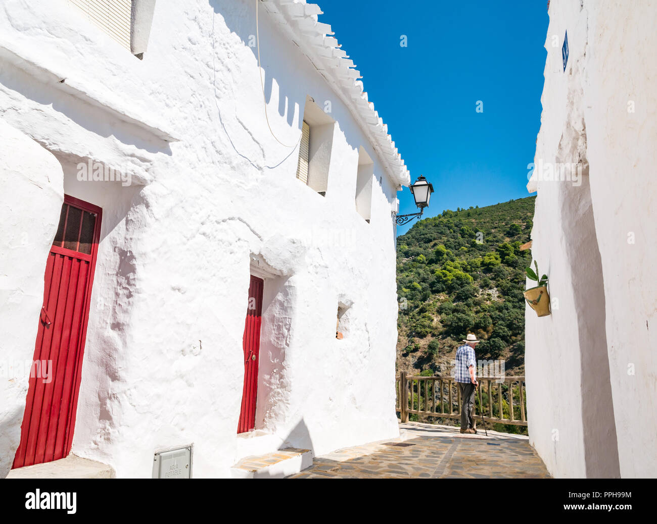 Vecchio uomo che indossa cappello di Panama accanto a case bianche ammirando mountain view nel vecchio villaggio di Moresco di Salares, Axarquia, Andalusia, Spagna Foto Stock