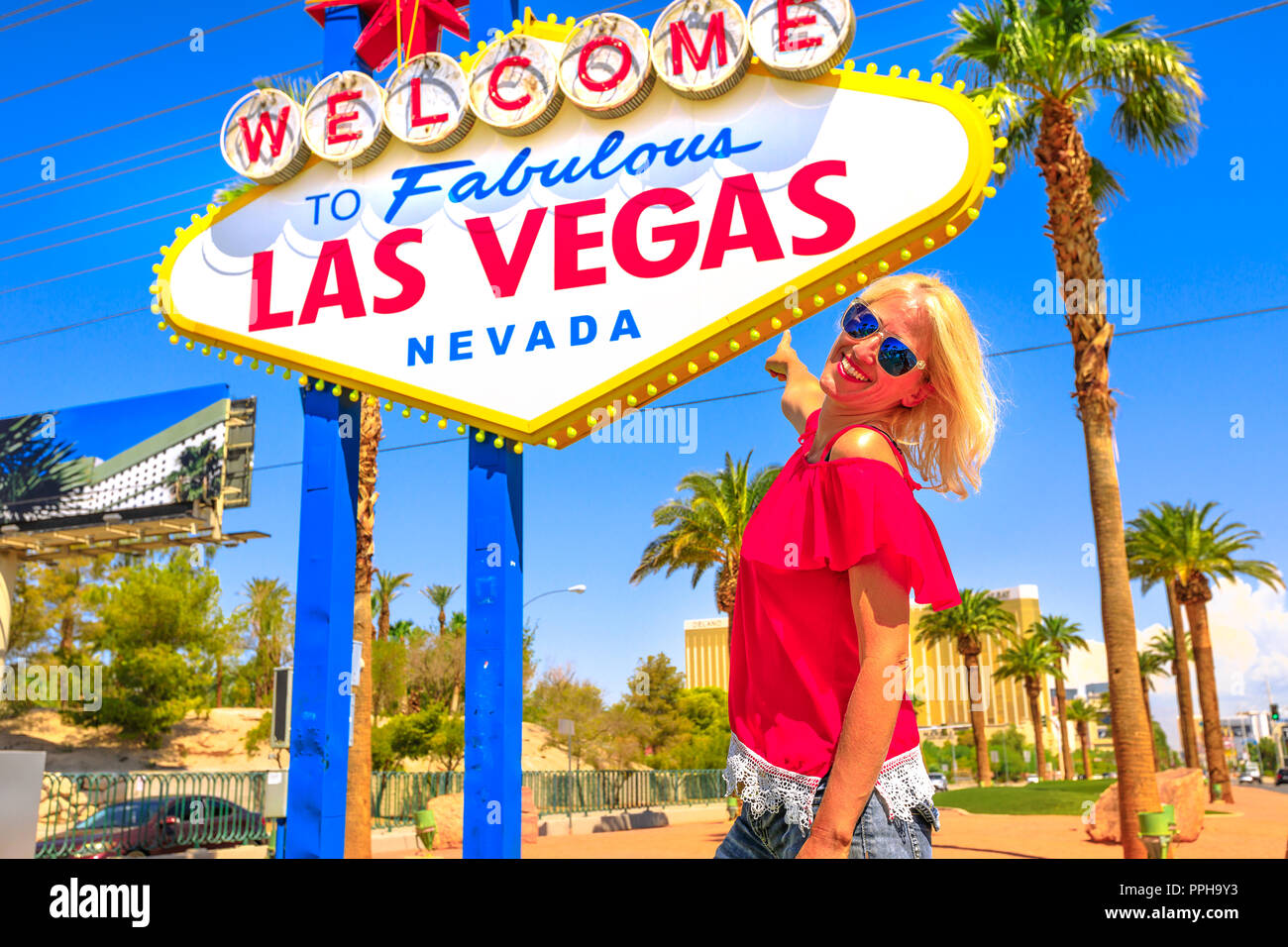 Felice donna turistica rivolta Benvenuto nella favolosa Las Vegas Nevada segno, un punto di riferimento sulla Strip di Las Vegas all'entrata della citta'. Meta turistica apprezzata in Nevada, Stati Uniti. Foto Stock