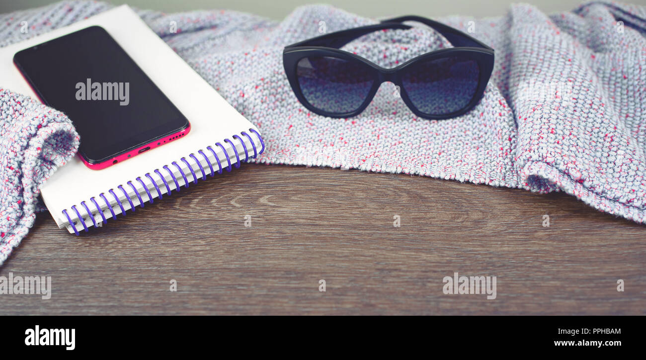 Banner spazio vuoto sul desktop mobile phone gadget Notepad occhiali da sole. Il vecchio legno naturale sfondo squallido coperta di maglia plaid color porpora ton Foto Stock