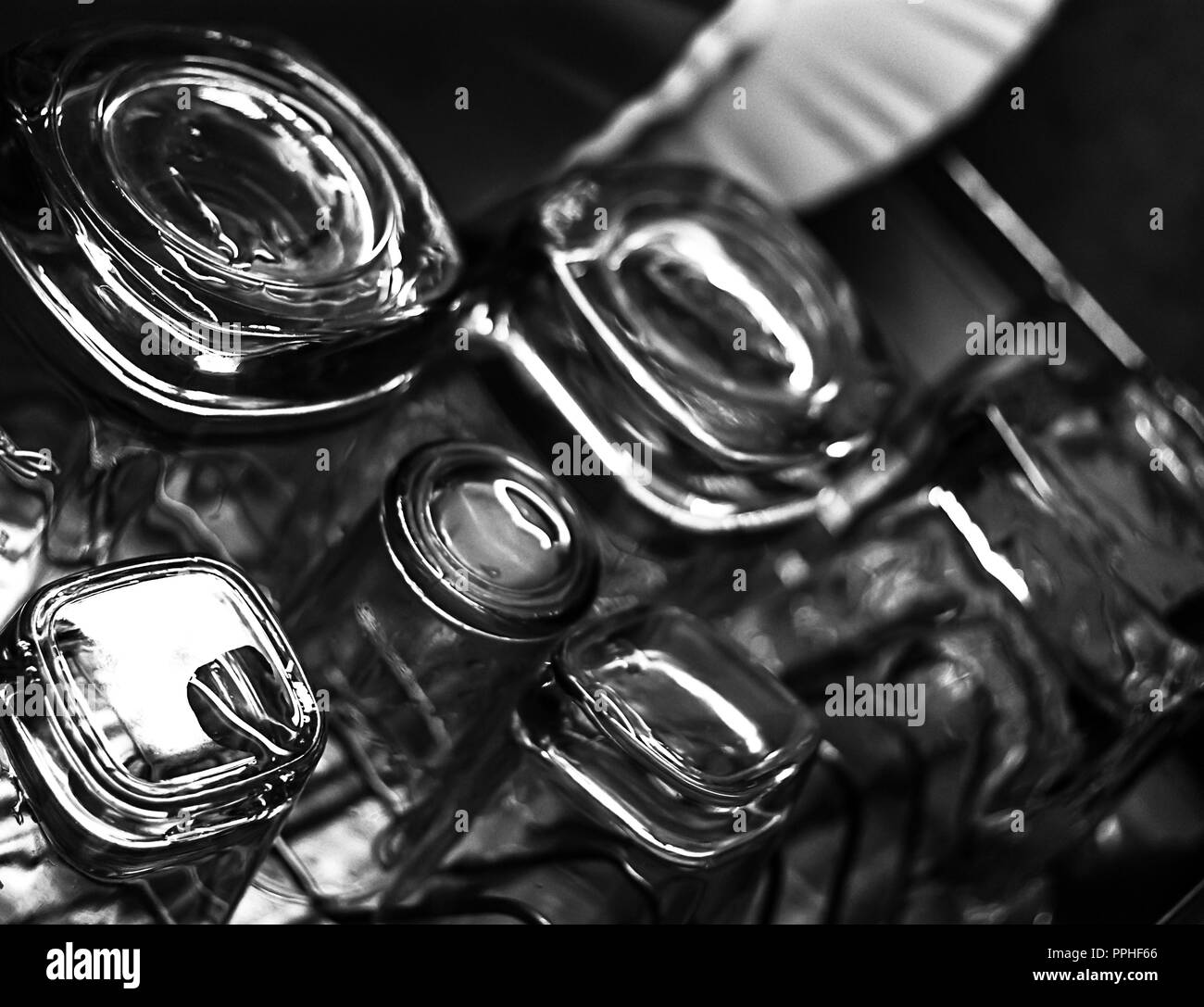 In bianco e nero di close-up immagine di whiskey in vecchio stile o rocce bicchieri lungo con shot o tiratore occhiali su un piatto sgocciolatoio in cucina Foto Stock