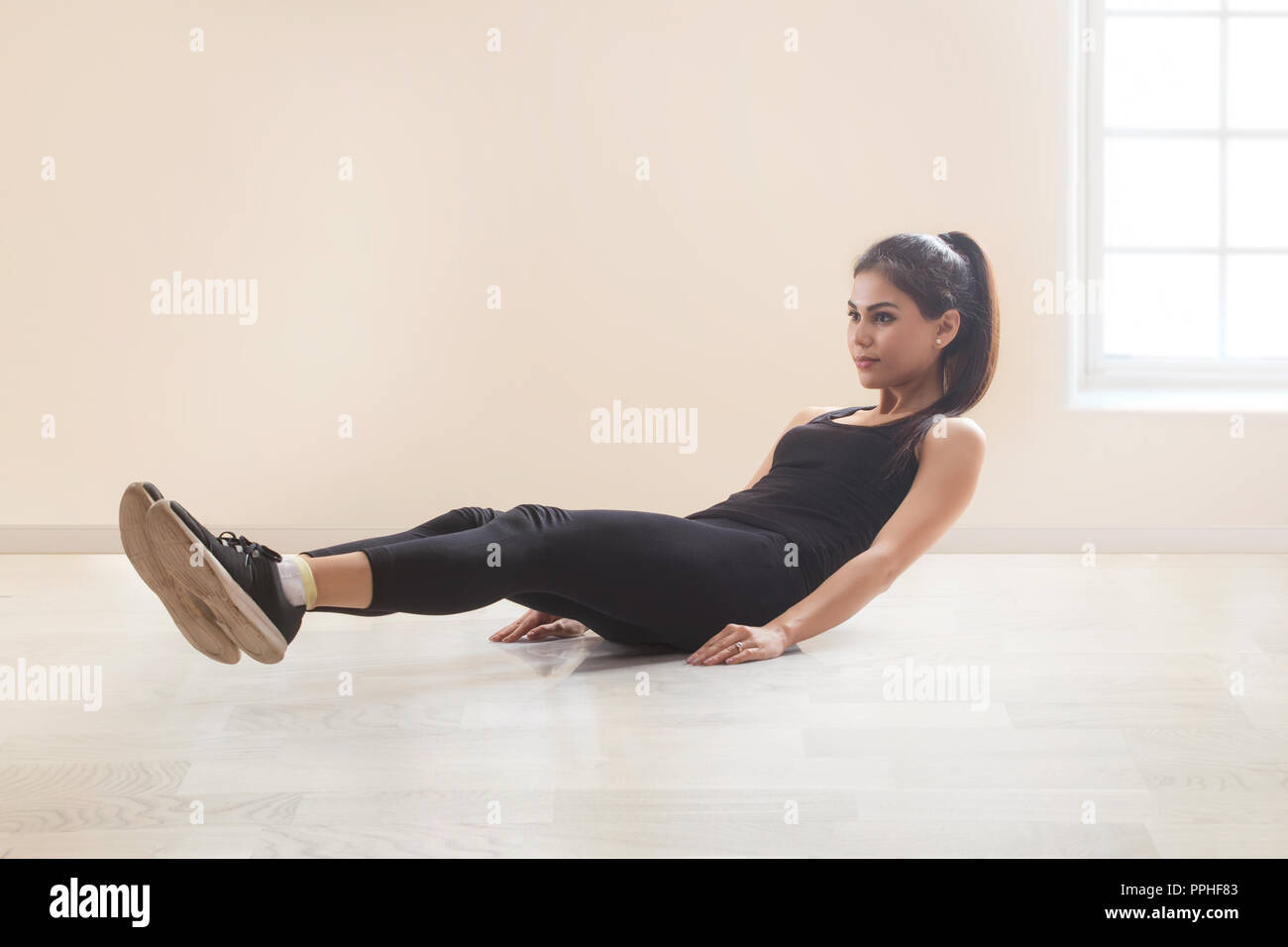 Giovane donna in abiti da allenamento facendo esercizi abs sul pavimento. Foto Stock