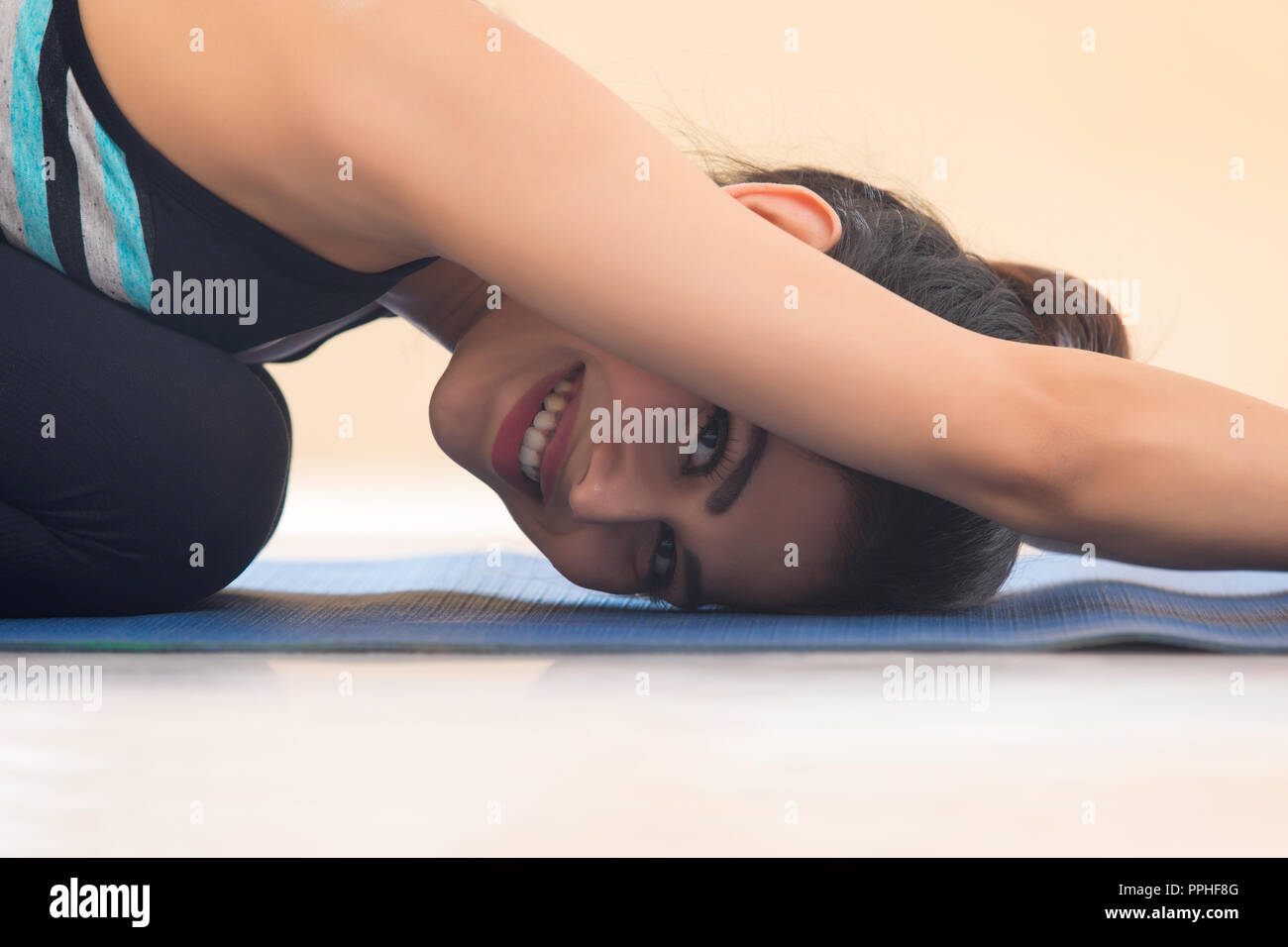 Close up di un sorridente giovane donna in postura yoga. Foto Stock