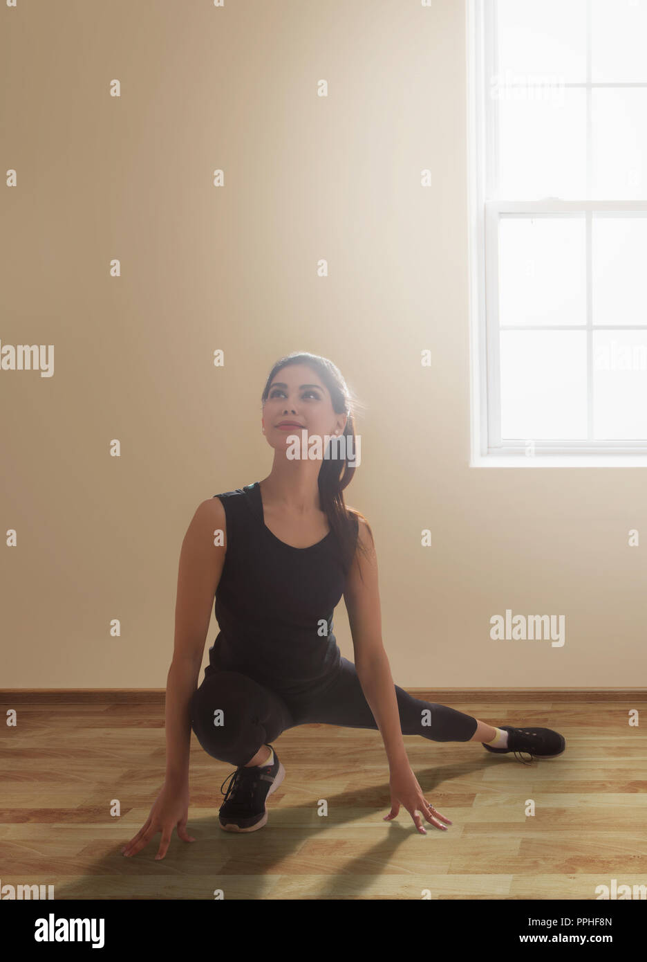 Giovane donna in abiti da allenamento facendo esercizi di stretching sul pavimento. Foto Stock