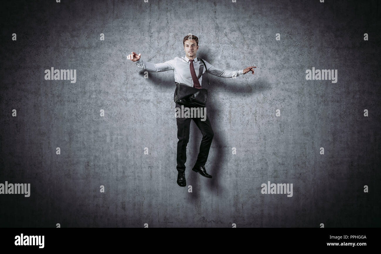 Sorridente imprenditore di salto e parete di cemento Foto Stock